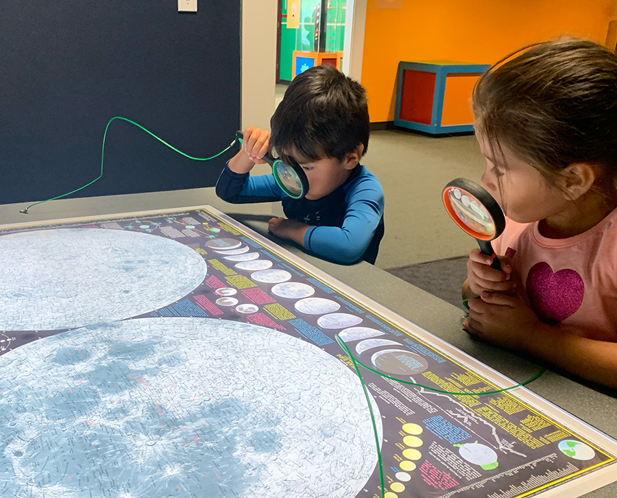Kids looking through magnifying glasses at the Moon Stages